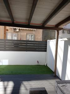 d'une terrasse avec clôture blanche et pelouse verte. dans l'établissement NY Central 2, à Patras