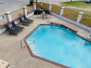 una gran piscina con sillas y una mesa en Magnolia Inn and Suites, en Magnolia