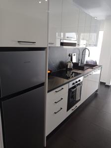 a kitchen with white cabinets and a black refrigerator at NY Central 2 in Patra