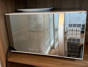 a microwave sitting on a shelf with a remote control at Hotel Brás in São Paulo