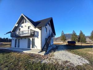 a white house with a balcony and a bench at CASA LENA -VATRA DORNEI in Vatra Dornei +24 photos