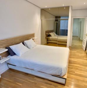 Habitación privada en Bilbao Centro في بلباو: غرفة نوم بسرير ابيض كبير ومرآة