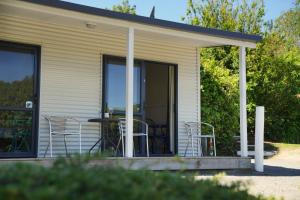 a house with chairs and a table on a porch at Akaroa Top 10 Holiday Park in Akaroa