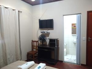 a living room with a television and a bathroom at Pousada do Ribeirão in Andrelândia