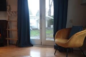 een woonkamer met een stoel en een glazen schuifdeur bij Chalet op mooie rustige plek in Enschede