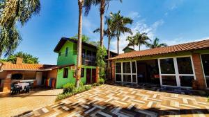 uma casa com palmeiras e um pátio em Pousada do Alemão em Foz do Iguaçu