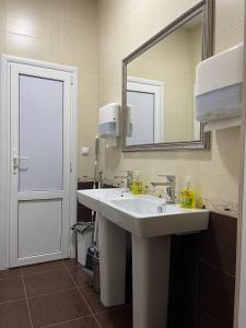 y baño con lavabo blanco y espejo. en Хостел "Сириус" en Kislovodsk