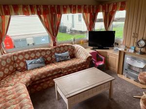 a living room with a couch and a tv at Dans Coastal Retreat in Chapel Saint Leonards
