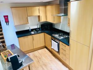 uma cozinha com armários de madeira e um forno com placa de fogão em Contemporary large apartment in an ideal location em Bath