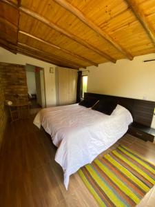 a bedroom with a large bed with a wooden ceiling at Cabaña Media Luna in Guatavita