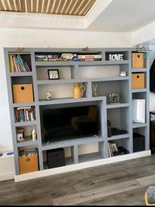 a living room with a television in a white shelf at The Salty Bee in South Hayling