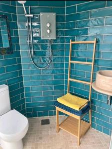 a blue tiled bathroom with a chair and a shower at The Salty Bee in South Hayling