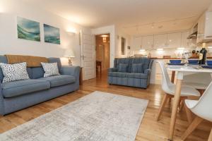 a living room with a blue couch and a kitchen at Harbour House Apartment in Wadebridge