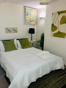 Luxury apartment in the heart of Bath في باث: غرفة نوم بسرير ذو شراشف بيضاء ومخدات خضراء