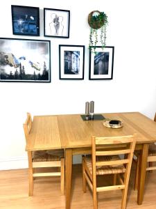 Luxury apartment in the heart of Bath في باث: طاولة طعام وكراسي خشبية مع صور على الحائط