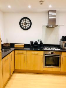 una cocina con armarios de madera y un reloj en la pared en Superbly located 2 bedroom luxury apartment, en Bath