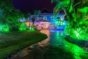een huis verlicht in de nacht met groene lichten bij O paraíso em Peruíbe Casa para até 25 pessoas in Peruíbe