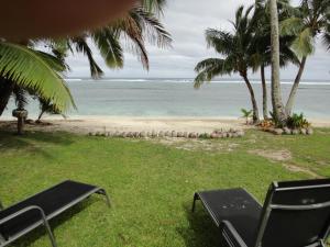 uma vista para uma praia com cadeiras e árvores e para o oceano em Betela Beach House em Rarotonga