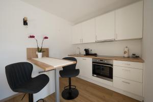 uma cozinha com armários brancos, uma mesa e duas cadeiras em Austrian Apartments em Bad Goisern