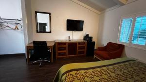 a bedroom with a desk and a bed and a tv at New American Inn & Suites in Anaheim +8 photos