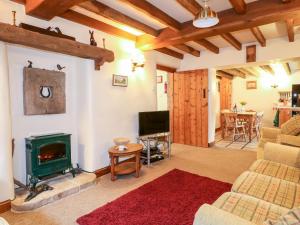 a living room with a fireplace and a tv at Oak Tree Cottage in Matlock