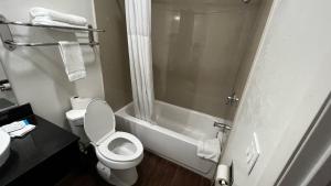 a bathroom with a toilet and a shower and a sink at New American Inn & Suites in Anaheim