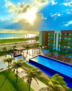 una piscina con palmeras frente a un edificio en Apartments Vg Fun Praia do Futuro, en Fortaleza