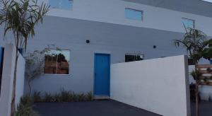 a white building with a blue door on it at Loft Pousada Sorriso in Sorriso
