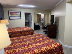 Cette chambre comprend deux lits et une télévision. dans l'établissement Royal Lodge, à Absecon