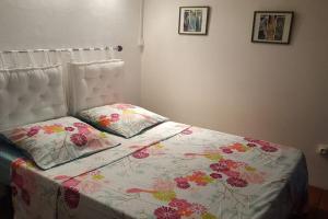 - un lit avec une couette à fleurs et 2 oreillers dans l'établissement BEAU STUDIO DUPLEX, à Les Trois-Îlets