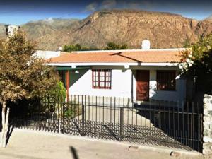a white house with a fence in front of a mountain at La Viñita in Cafayate