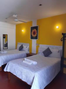 Hotel Doña Mary Huatulco في سانتا كروز هواتولكو: غرفة بسريرين وجدار اصفر