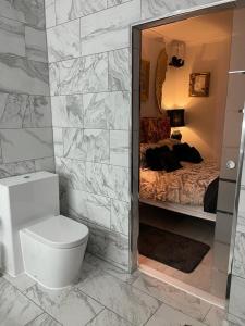 a bathroom with a toilet and a bed with a mirror at Olivia House in Porthcawl