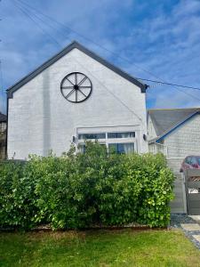Una casa blanca con un reloj al costado. en The Old Workshop - Drift en Penzance