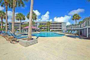 ein Resortpool mit Liegestühlen und Palmen in der Unterkunft Mariners Cay 26 in Folly Beach