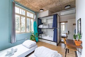 a dorm room with two beds and a desk and a surfboard at Selina Neve Tzedek Tel Aviv in Tel Aviv