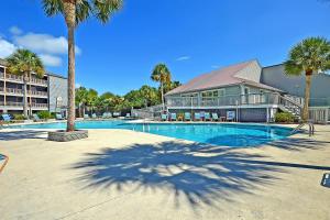 a swimming pool with palm trees and a building at Mariners Cay 68 in Folly Beach