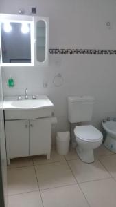 La salle de bains blanche est pourvue d'un lavabo et de toilettes. dans l'établissement "COMO EN CASA" Duplex 2 Lisandro de la Torre 79, à San Rafael