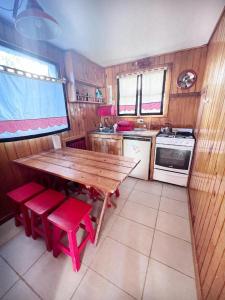 cocina con mesa de madera y sillas rojas en Cabaña Departamento CERRO CATEDRAL Mínimo 5 NOCHES en San Carlos de Bariloche