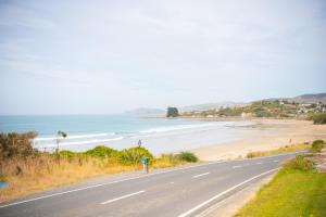 a road next to a beach with the ocean at The Salty Bushman B&B in Kaka Point