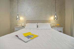 a book on a white bed with two lights at Hotel Grotta in Naxos Chora
