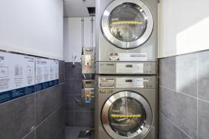 two washing machines in a laundry room with a wall at Nine Tree Hotel Myeongdong in Seoul