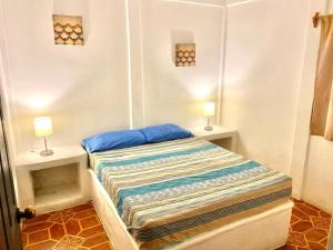 a small bedroom with a bed with two lamps on it at Arcadia Cabañas Vacacionales in Retalhuleu +21 photos