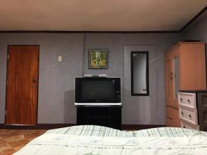 Pinoykano home في Candijay: غرفة نوم مع سرير وتلفزيون بشاشة مسطحة