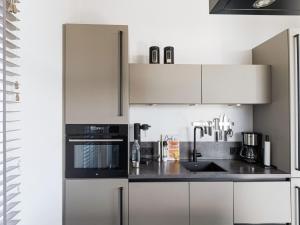 een keuken met witte kasten en een zwart apparaat bij Family villa with garden and jetty in Zeewolde
