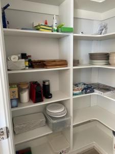 a white pantry with plates and dishes on shelves at ARIA Emu Bay Seaside KI@43 in Emu Bay
