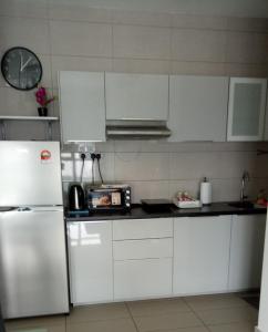 a kitchen with white cabinets and a white refrigerator at Schott Place@Conezion IOI Resort City Putrajaya in Putrajaya