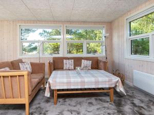 a living room with a table and a couch and windows at 6 person holiday home in R m in Bolilmark