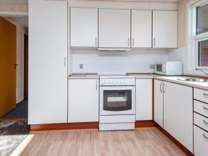 een keuken met witte kasten en een witte oven bij 6 person holiday home in R m in Bolilmark