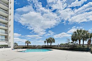 a swimming pool in front of a building with palm trees at Kingston Plantation Unit 706 in Myrtle Beach